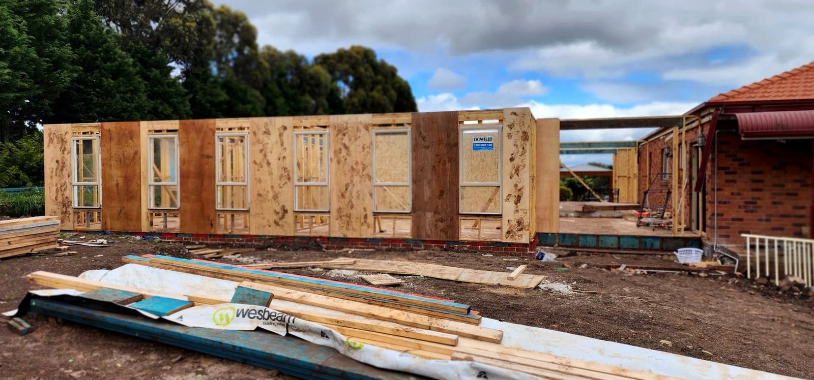 Timber wall frames stood beside an existing brick home on a Melbourne extension - Master Framers